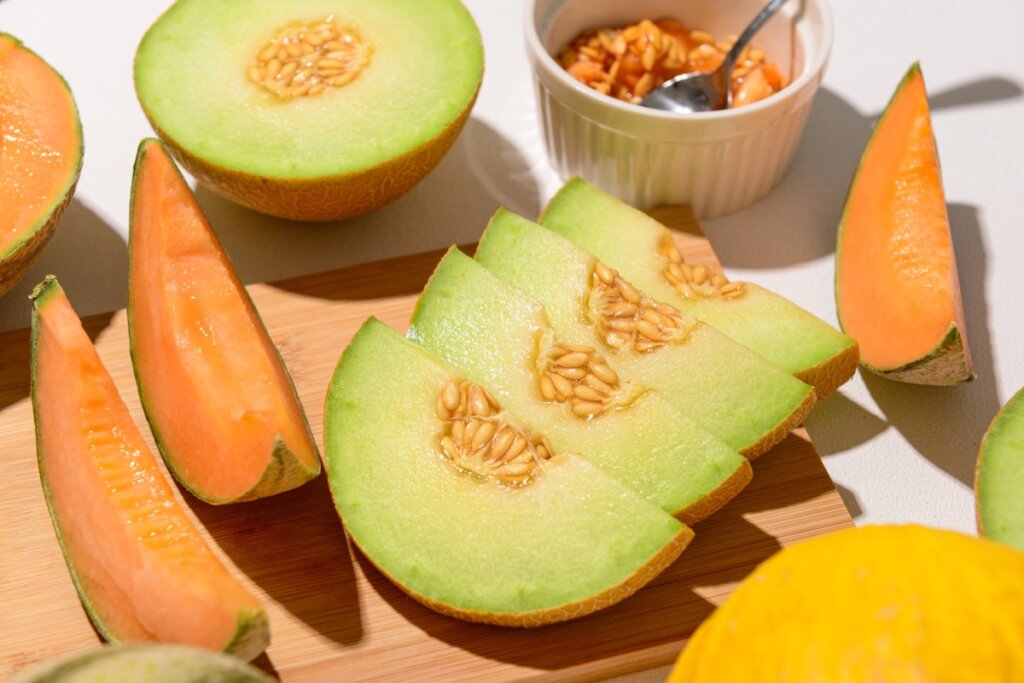 Diferentes tipos de melão fatiados sobre uma tábua de madeira