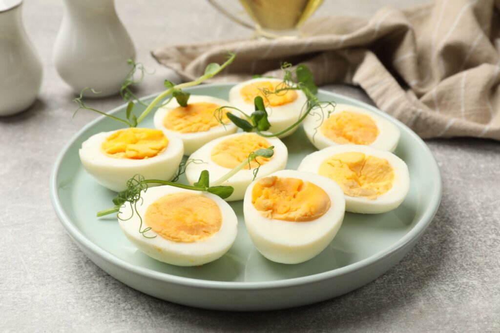 Ovos cozidos em um prato verde-claro sobre uma mesa branca