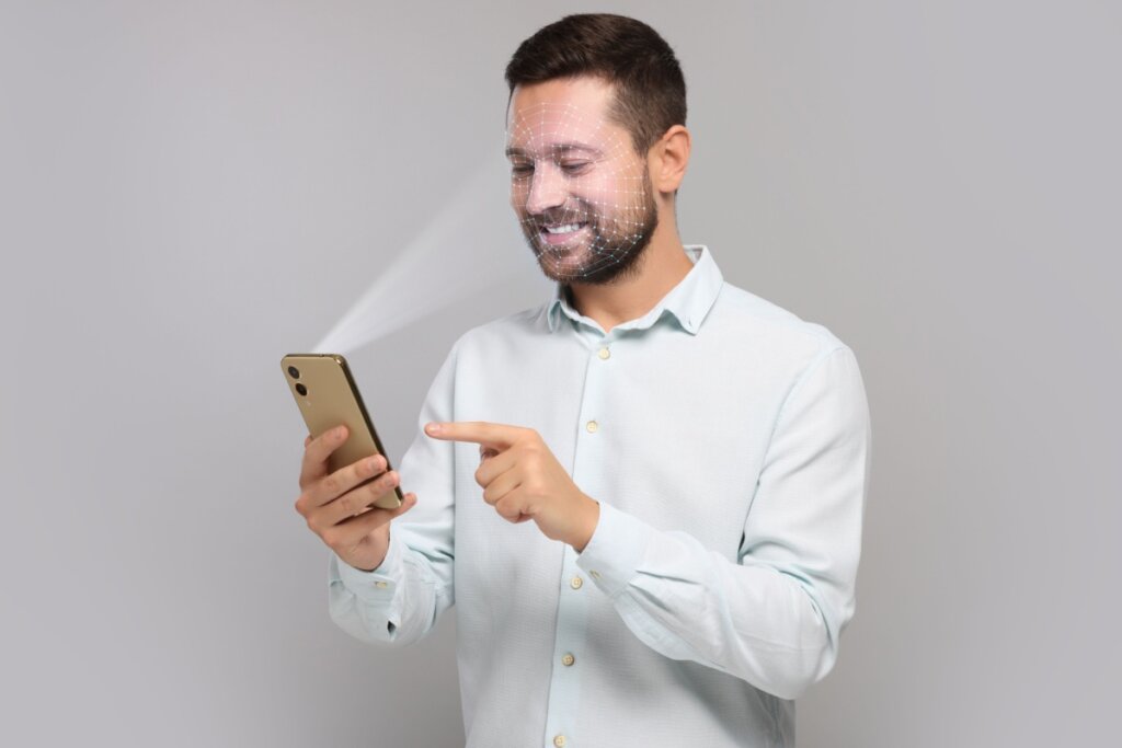 Homem, usando camisa branca, fazendo reconhecimento facial em um celular 