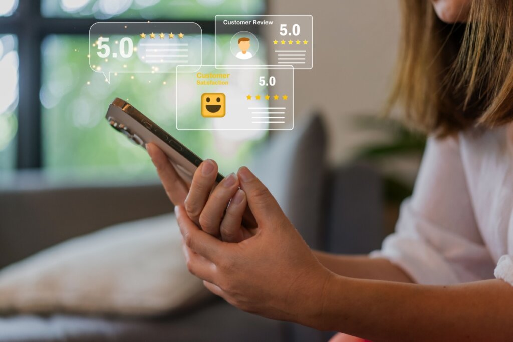 Pessoa segurando um celular e ilustração de review de compras em cima dele 