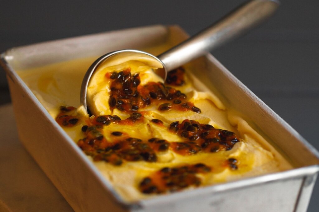 sorvete de maracujá em uma tigela retangular com caroços do maracujá decorando o sorvete