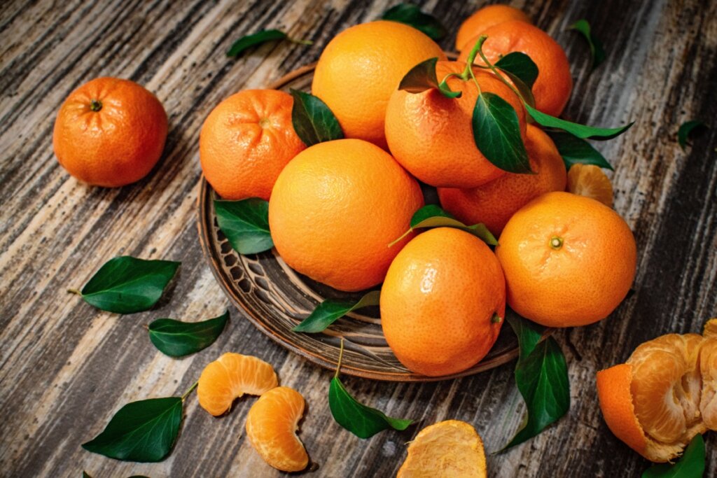 tangerinas empilhadas com folhas verdes em prato de madeira