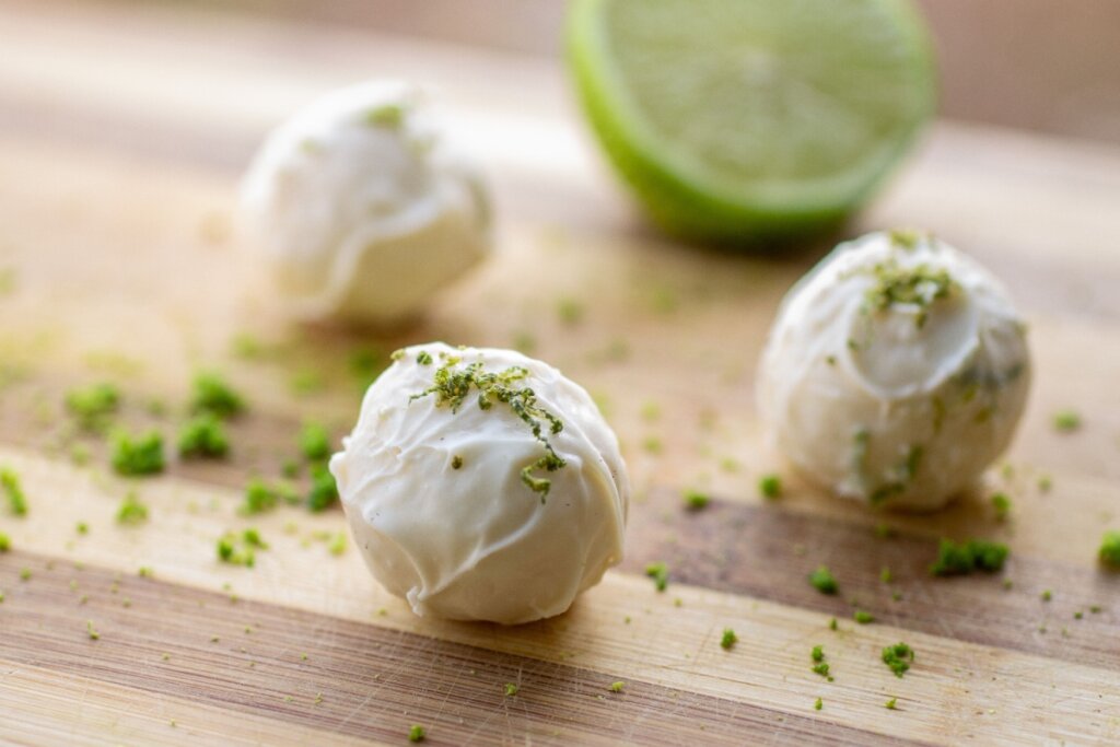 Trufas com cobertura branca e raspas de limão-siliciano em superfície de madeira 