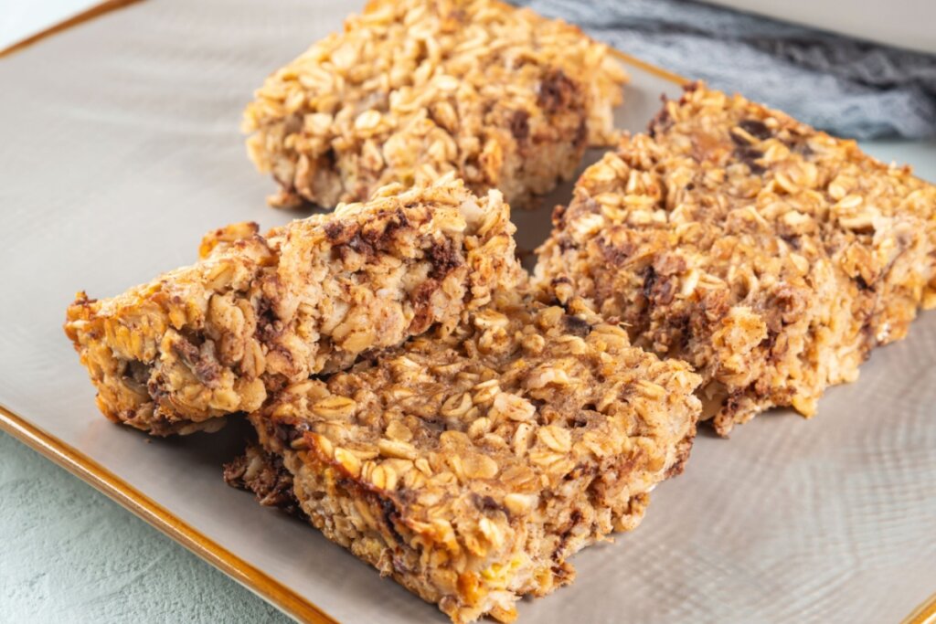 Barrinhas assadas de aveia com banana, textura rústica e dourada, servidas em pedaços