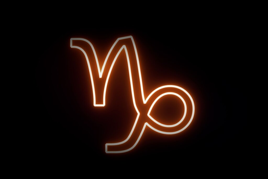 Ilustração digital do símbolo de Capricórnio (uma forma complexa que mistura um "V" com uma cauda curvada em laço). O símbolo tem um contorno brilhante em neon laranja e branco sobre um fundo preto.