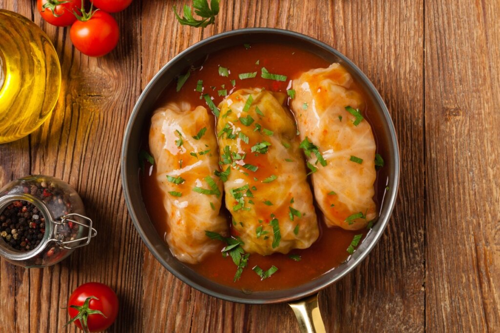 Charutos de repolho recheados com carne e arroz servidos em molho amarronzado com ervas frescas