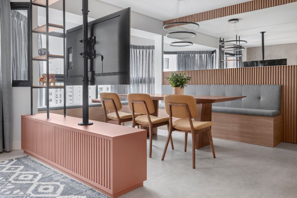 Sala de estar integrada com sala de jantar com uma televisão, mesa e cadeiras de madeira