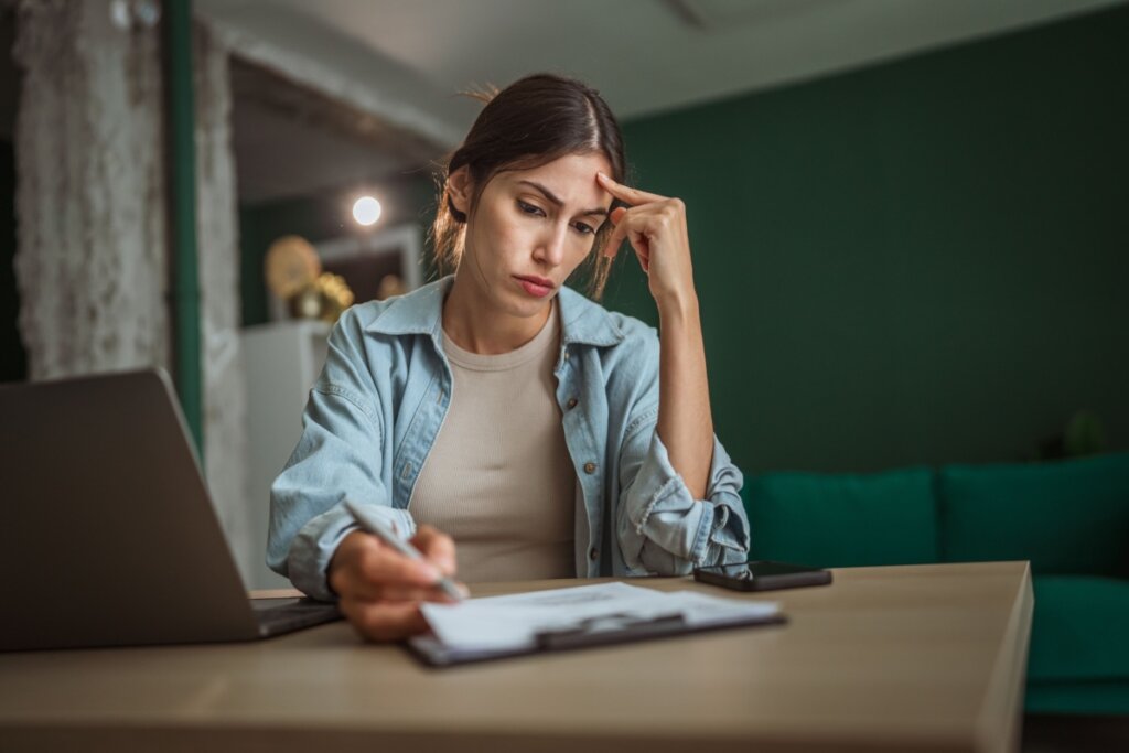 Mulher sentada e com uma das mãos apoiada na cabeça 