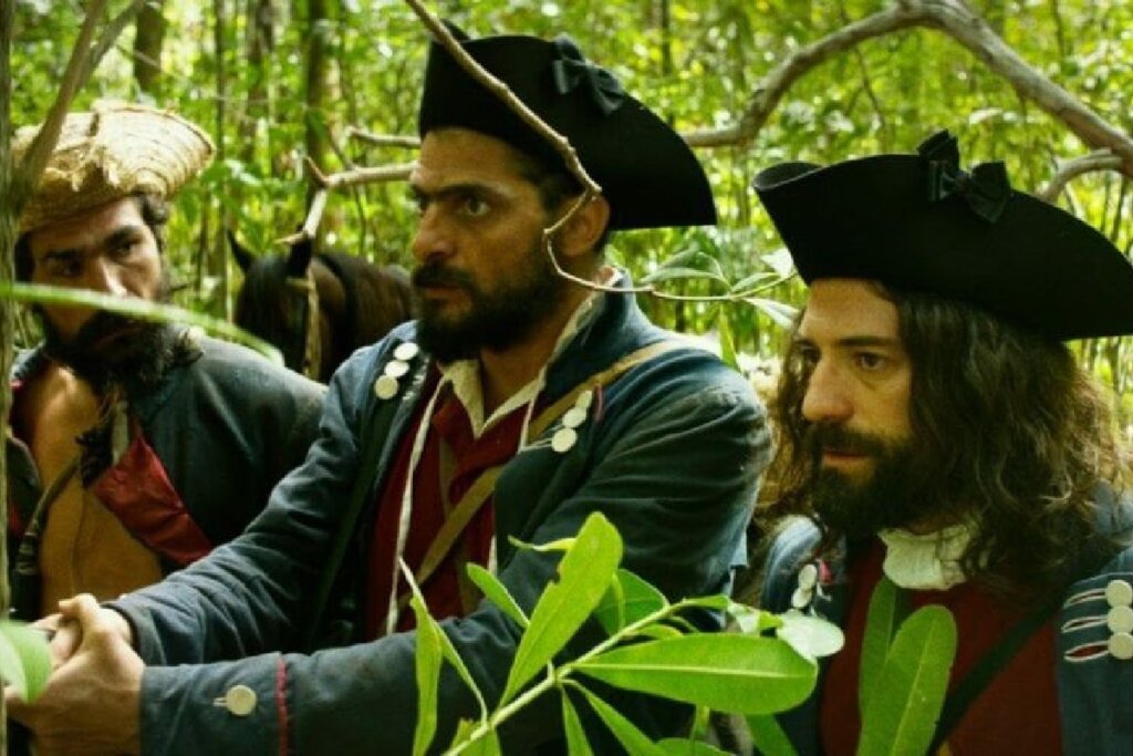 Cena do filme "Joaquim". Os homens estão em florestas com roupa da época