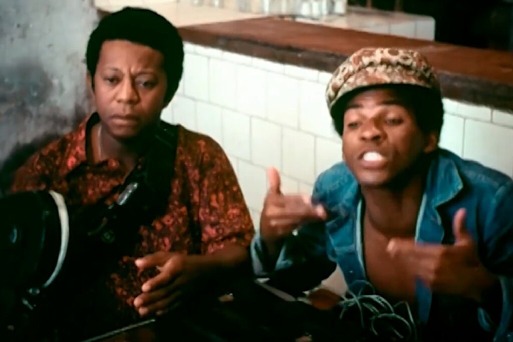 Cena do filme "Ladrões de Cinema", em que dois personagens do morro do Pavãozinho estão sentados conversando