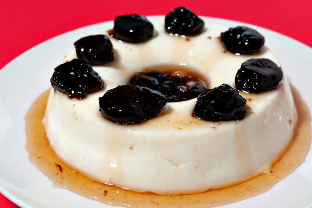 Manjar de coco com uva-passas em um prato branco 