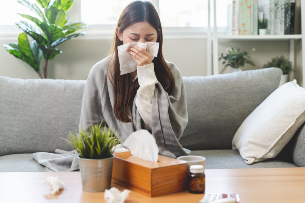 Mulher resfriada com papel tapando a boca e o nariz