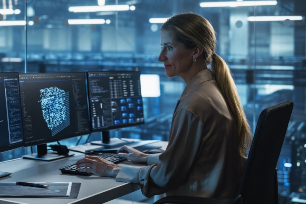 Mulher sentada em um escritório e mexendo em dados em um computador