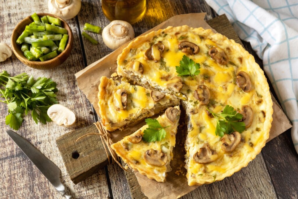 Quiche de cogumelos com vagem e queijo gratinado servida em mesa rústica com ervas frescas ao lado