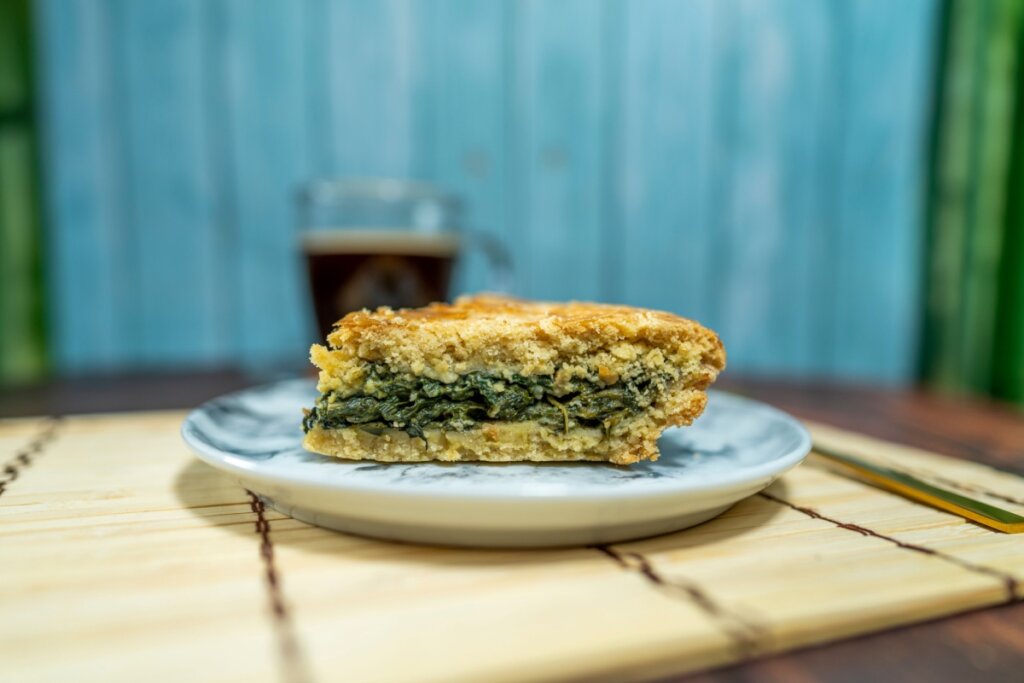 Pedaço de torta de grão-de-bico com acelga em um prato branco e azul 