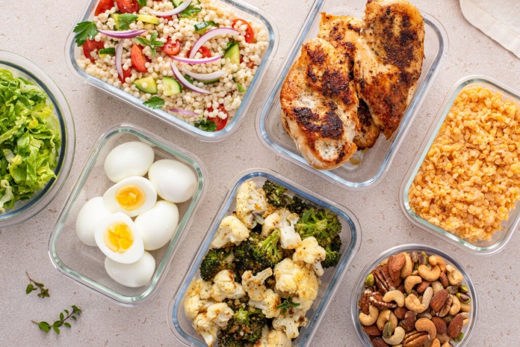 potes de vidro com alimentos ricos em proteína como frango, ovo, brócolis, castanhas