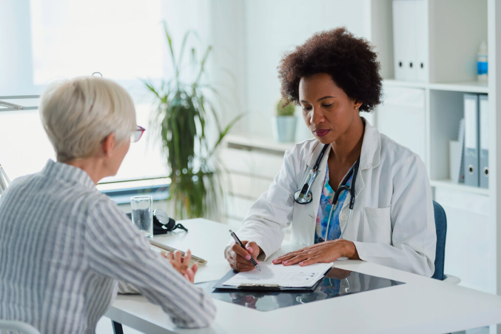 Médica realizando consulta com paciente em consultório.