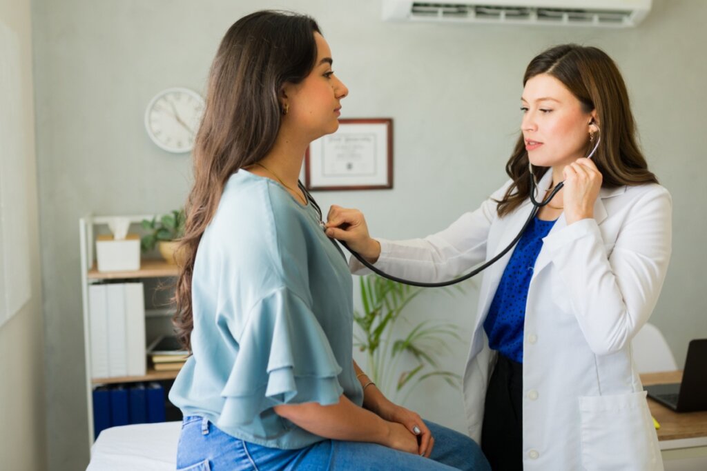 Médica examinando uma mulher com um estetoscópio 