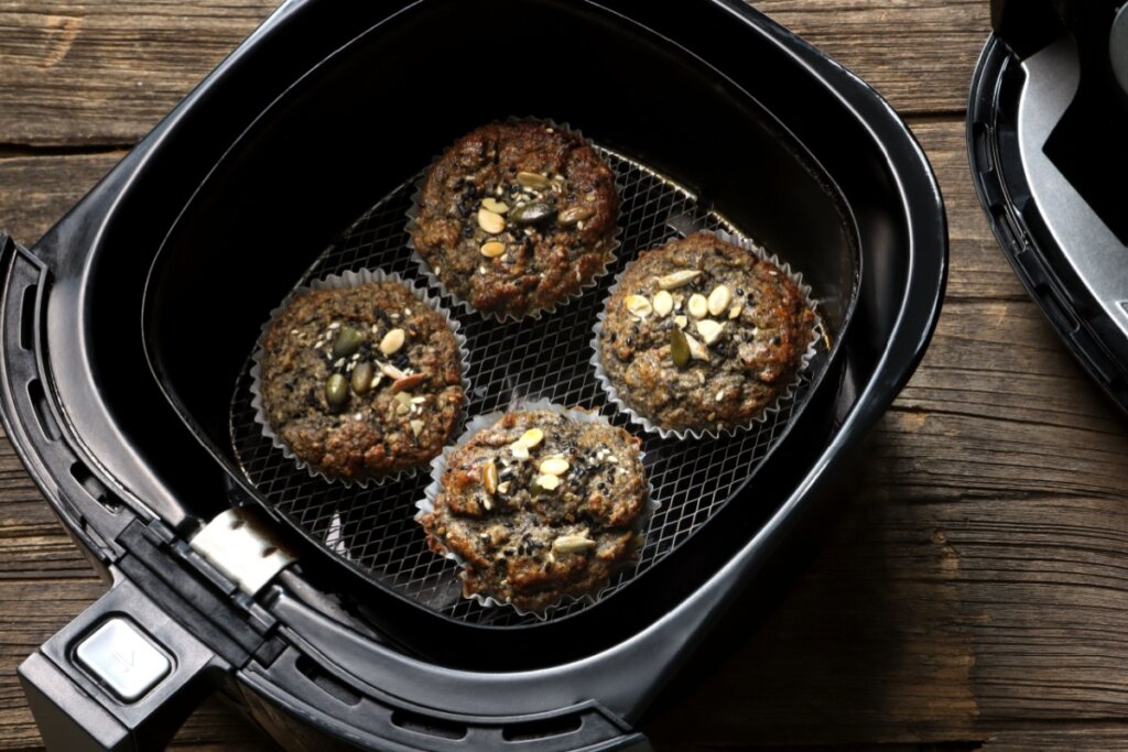 Muffin salgado de chia e sementes dentro de cesta de air fryer em cima de mesa de madeira