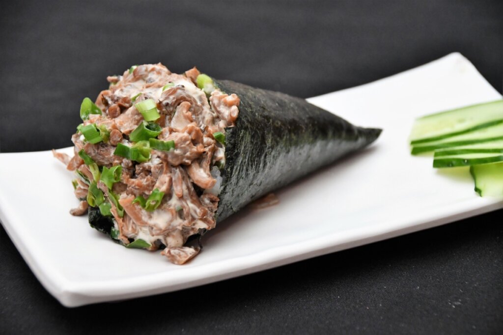 Temaki de shimeji servido em prato retangular branco em cima de bancada preta