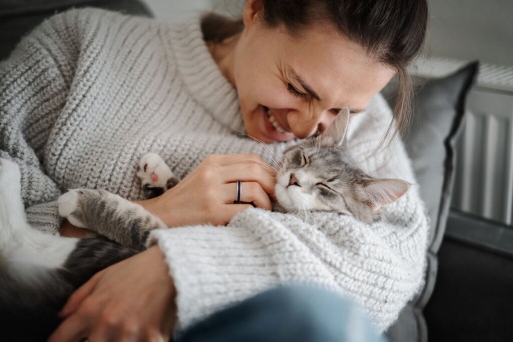 Tutora sorrindo com gato dormindo no colo