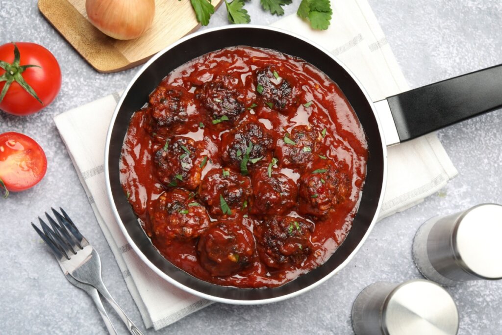 Frigideira com almôndega de feijão-preto com molho de tomate sobre pano branco em mesa cinza