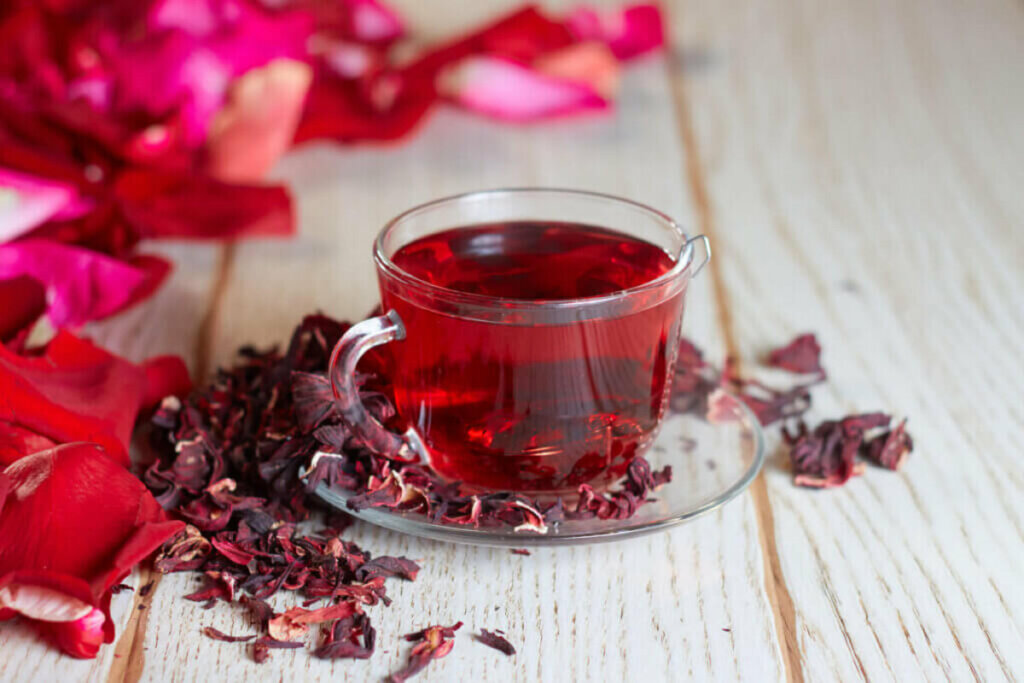 Chá de hibisco em uma xícara de vidro sobre uma mesa branca