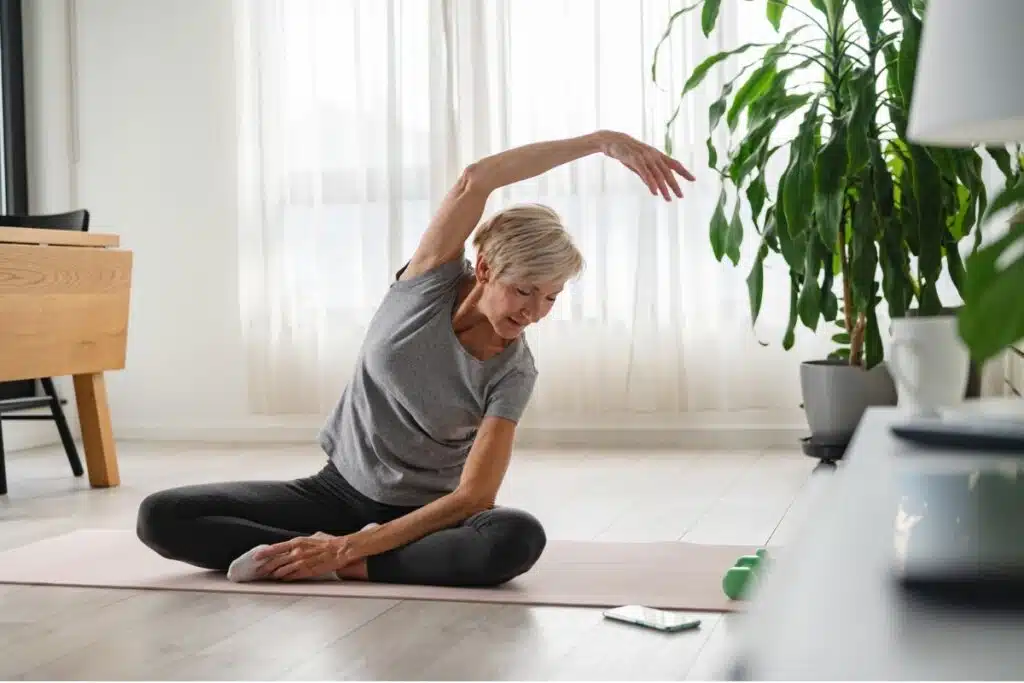 Mulher de meia-idade fazendo Yoga em uma sala de estar