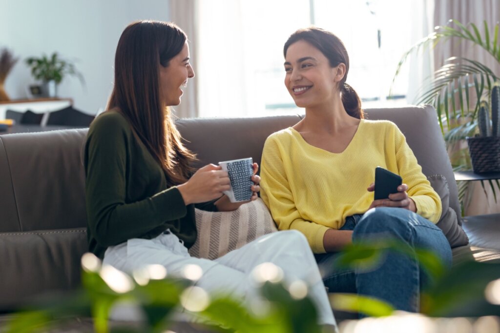 Amigas sentadas no sofá conversando e tomando café