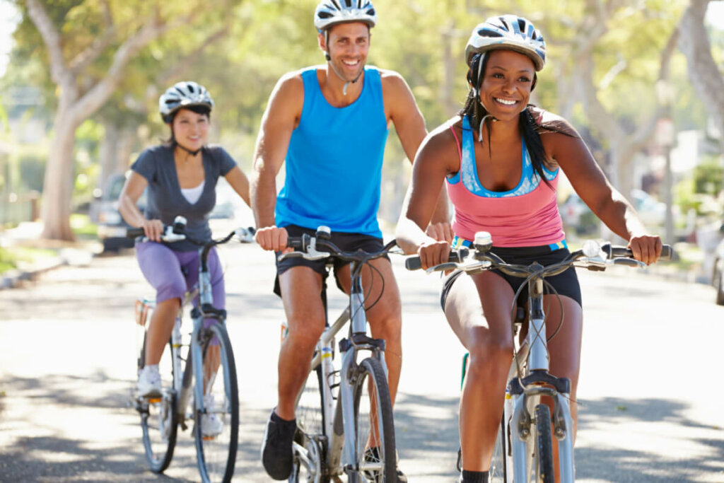 Duas mulheres e um homem andando de bicicleta na rua