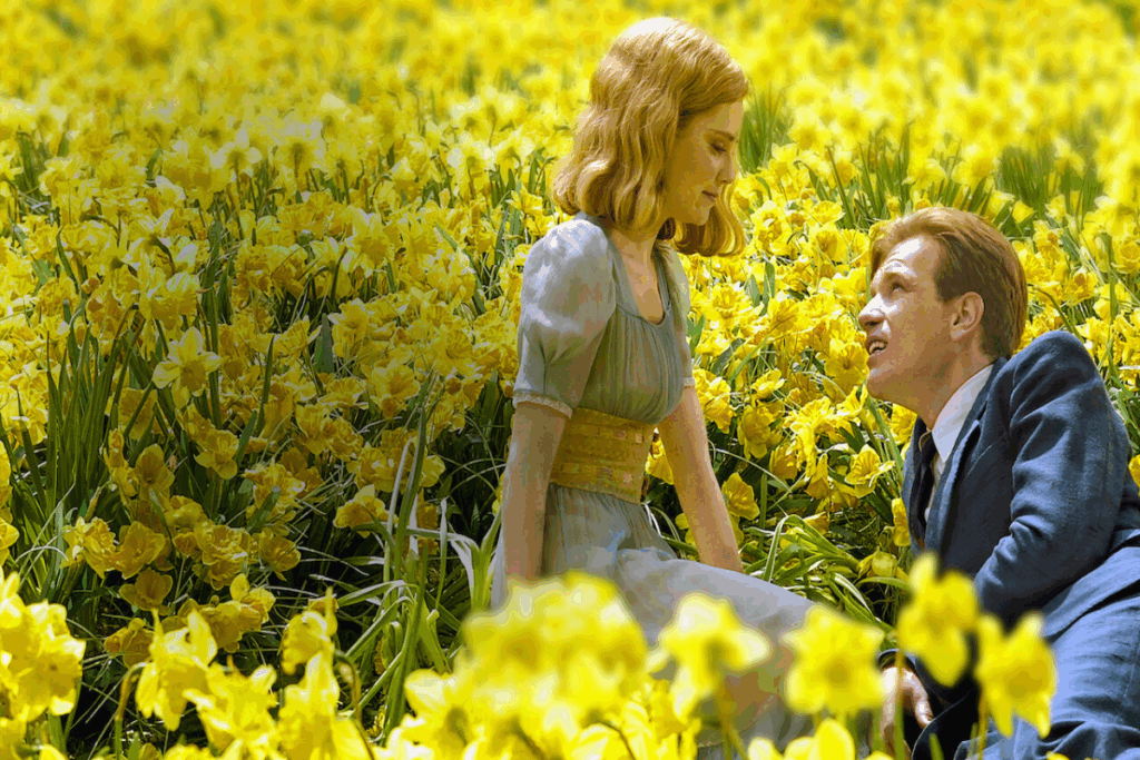Casal usando roupas de época deitados em jardim repleto de flores amarelas