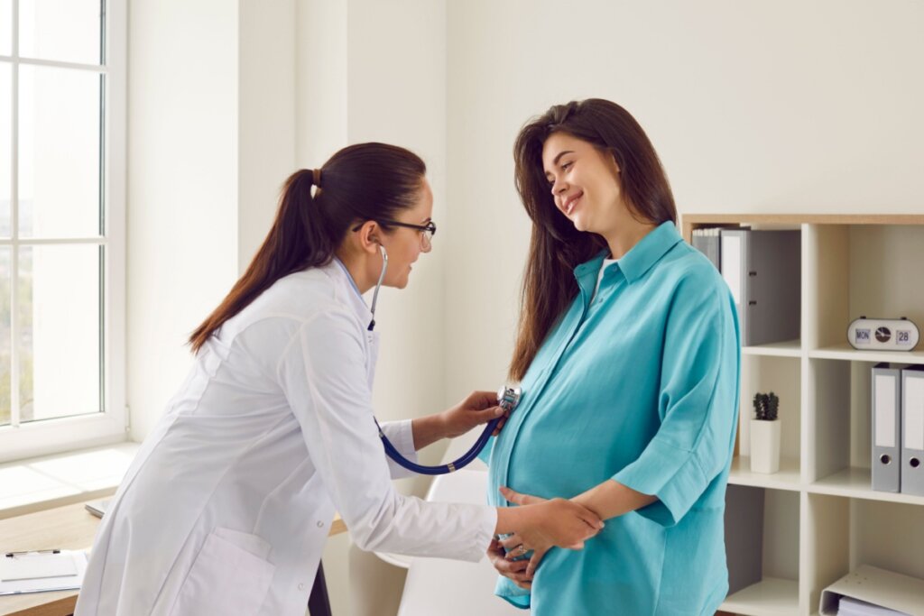 Médica consultando uma mulher grávida com um estetoscópio
