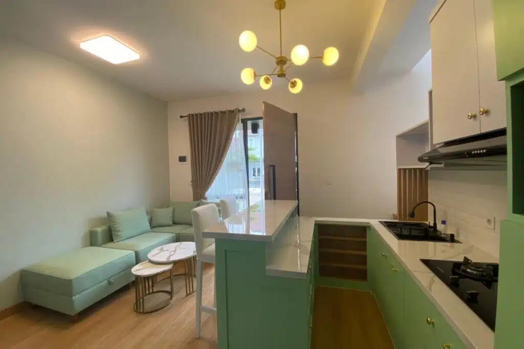 Sala de estar integrada à cozinha com sofá em tom verde-claro, bancada americana e móveis planejados