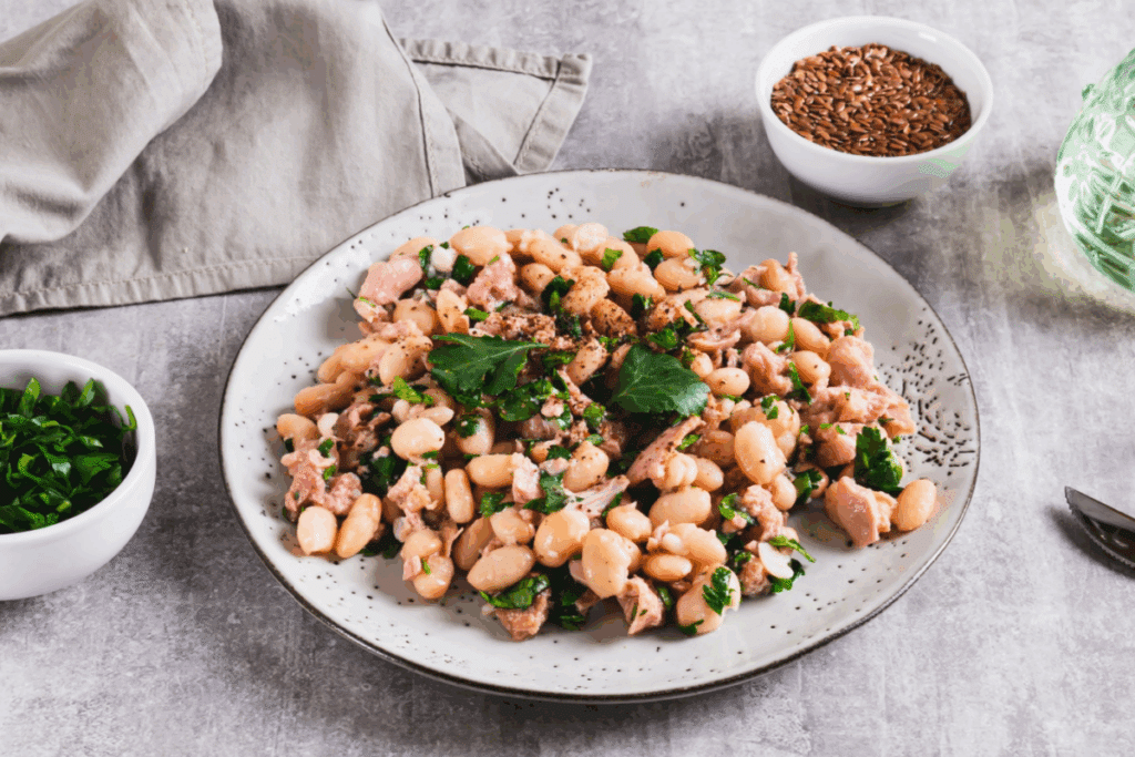 Prato branco com salada de feijão-branco com atum e folhas verdes