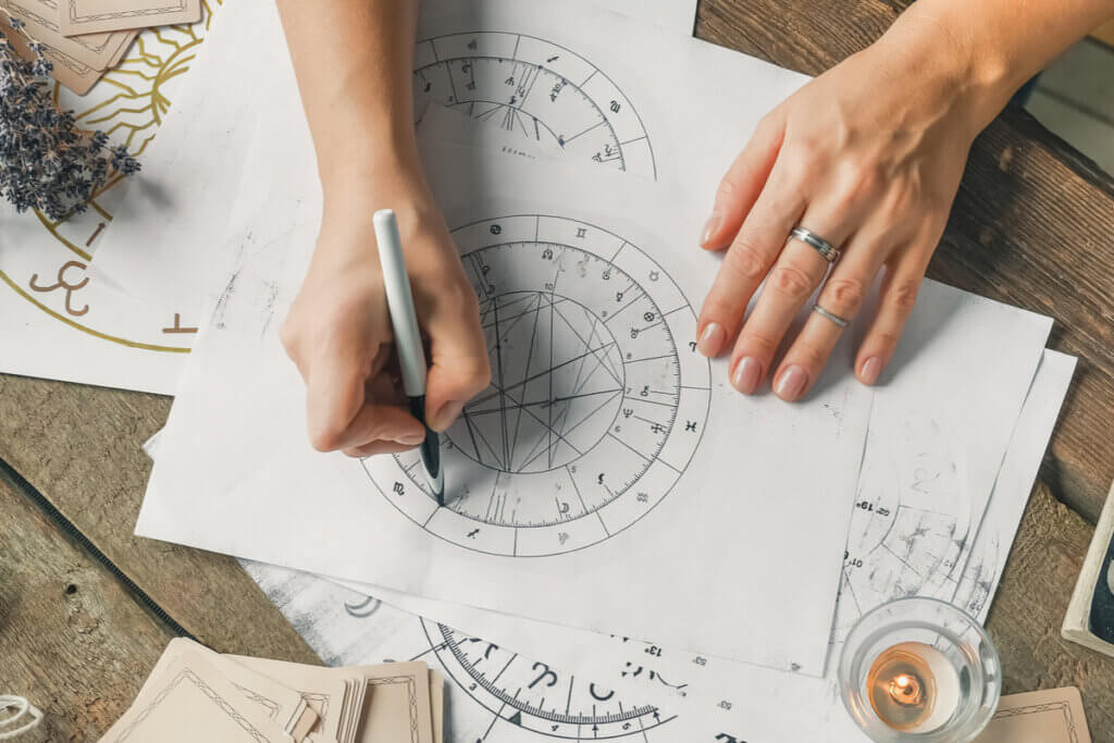 Mãos feminina fazendo um mapa astral em folha branca