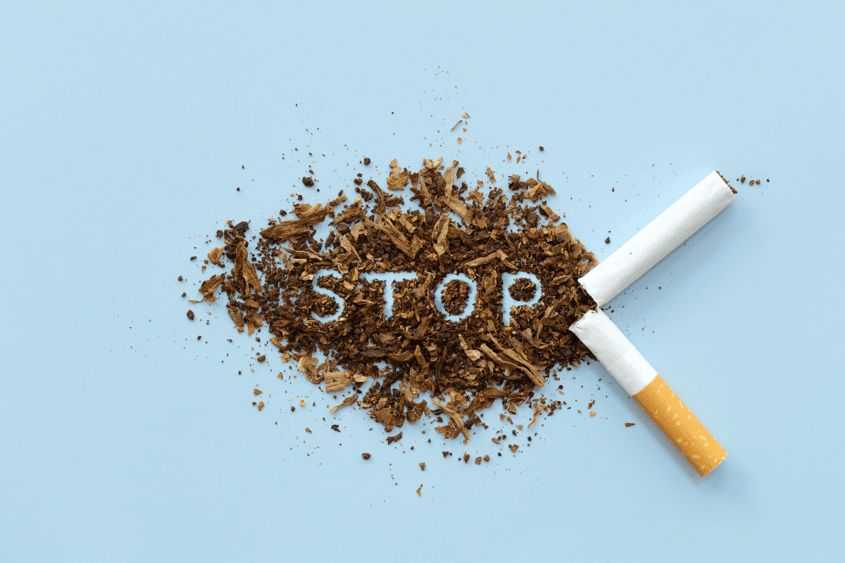 Imagem de cigarro quebrado ao meio e conteúdo do cigarro formando a palavra stop em fundo azul claro