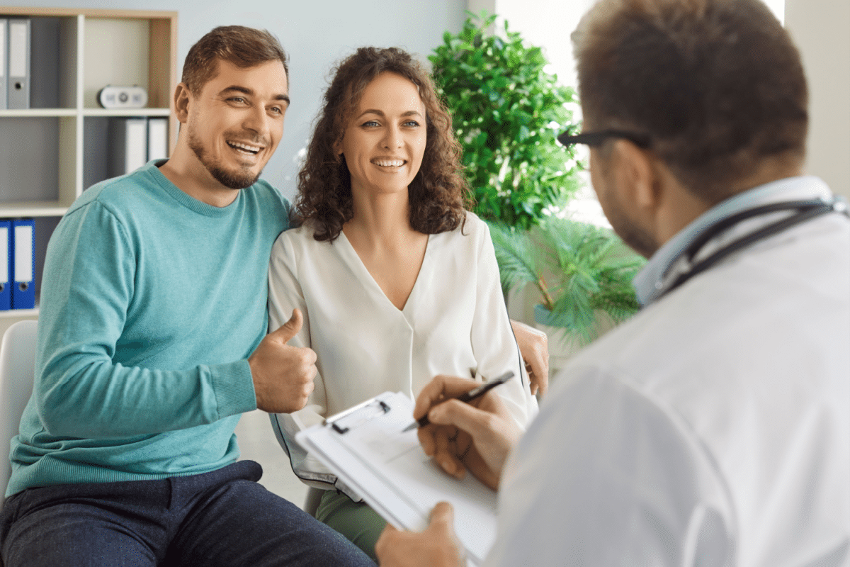 Casal em um consultório conversando com médica. Ambos sentados