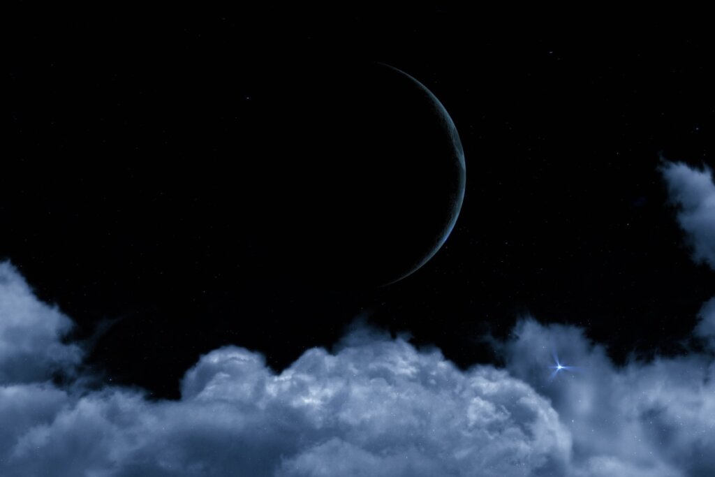 Imagem do céu noturno escuro exibindo uma fina borda prateada da Lua à direita. Na metade inferior, grandes nuvens volumosas de tom azul-acinzentado formam uma base, com uma estrela azulada bastante brilhante reluzindo entre elas à direita.