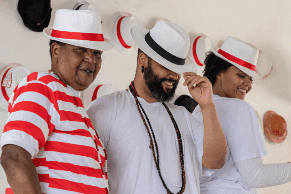 Dois homens e uma mulher usando chapéu e roupas branco e vermelho representando Zé Pelintra 