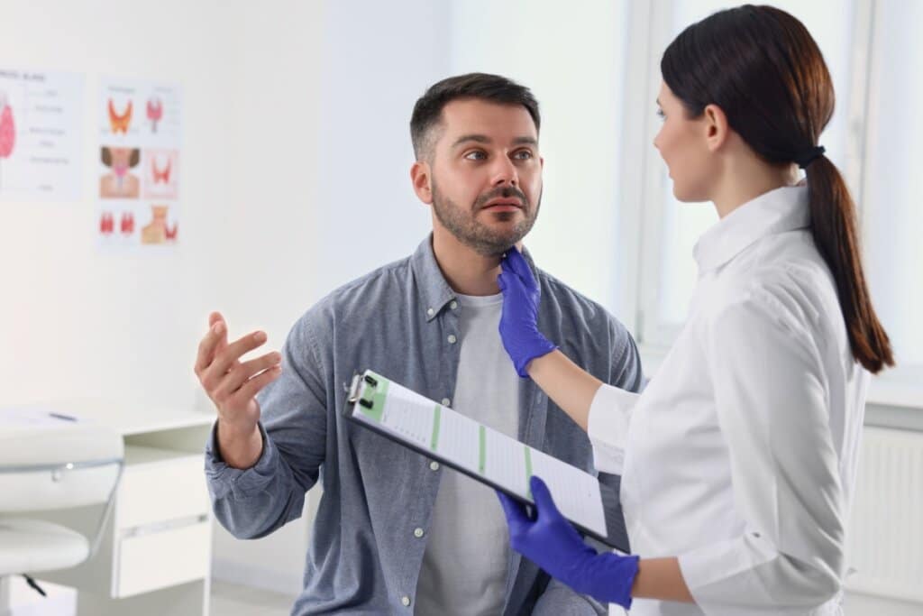 Profissional de saúde examinando a região do pescoço de um paciente durante avaliação de nódulos tireoidianos