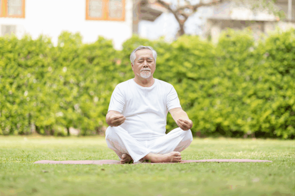 Homem de meia-idade, usando camisa e calça branca, meditando em um jardim