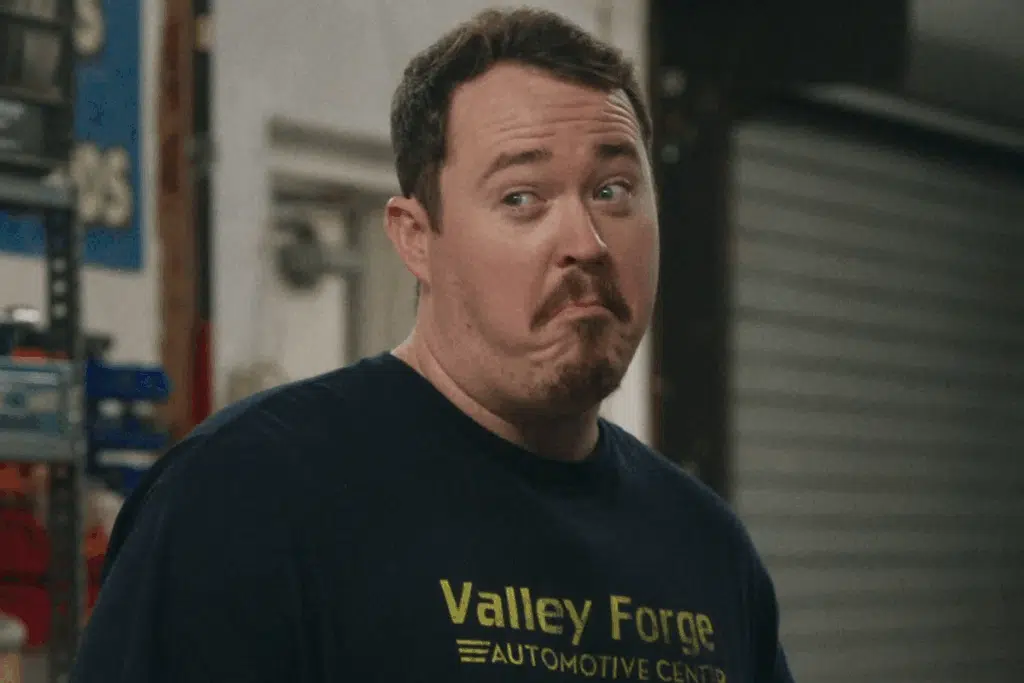 Homem de camiseta preta com a inscrição "Valley Forge" fazendo uma careta cômica e duvidosa.