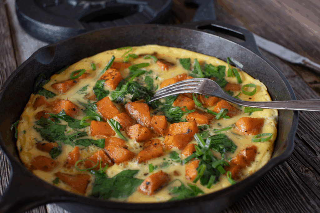 Omelete com batata-doce e espinafre em frigideira preta