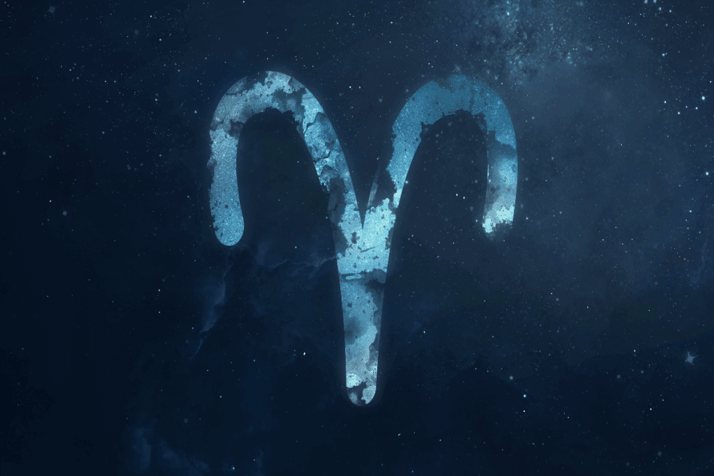 A imagem mostra o símbolo do signo de áries em destaque sobre um fundo que representa o espaço, repleto de estrelas e nebulosas. O ícone aparece em tons de azul, com textura que se mistura ao cenário cósmico.