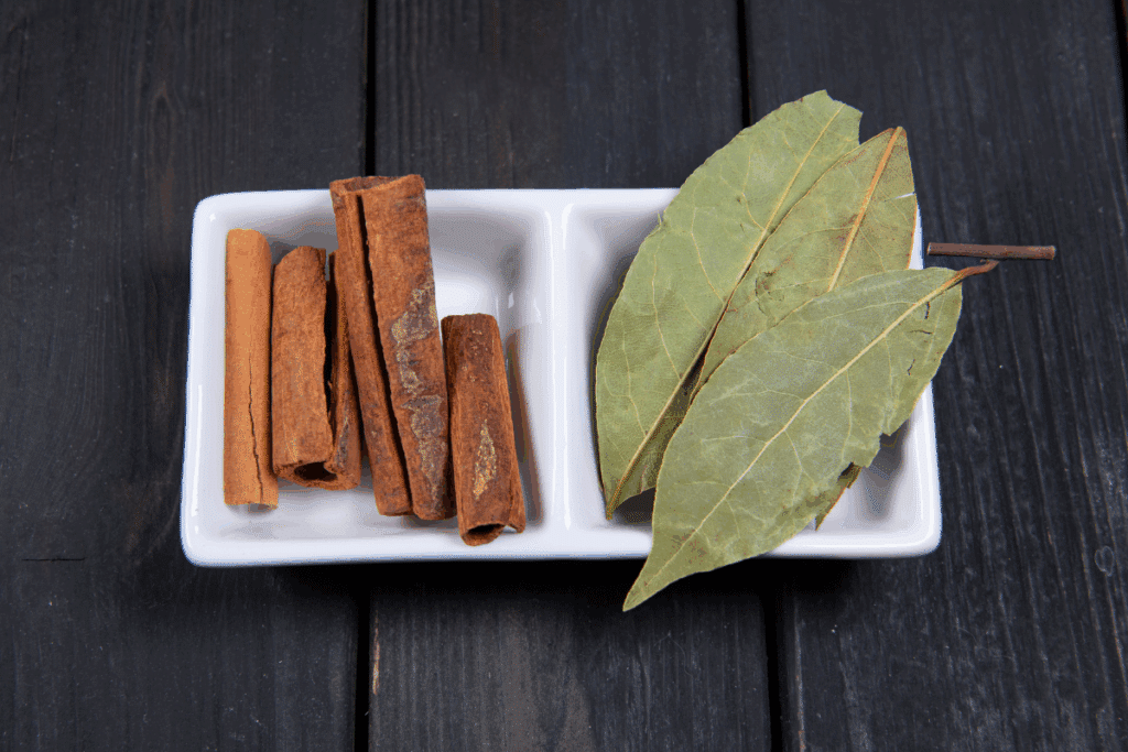 Recipiente branco com canelas em pau e folhas de louro