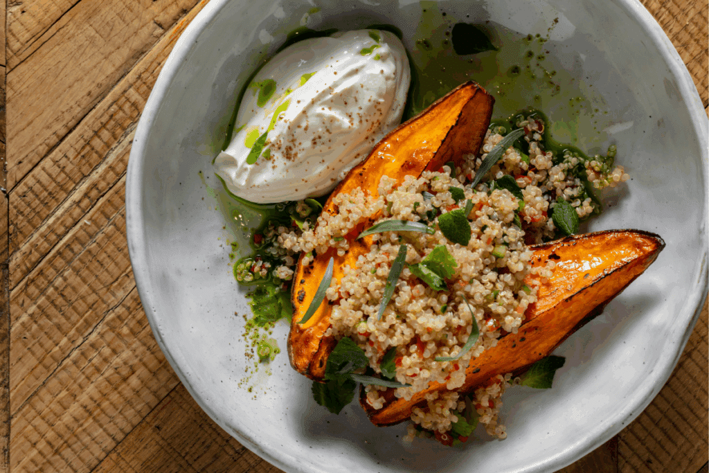 Batata-doce com cuscuz de quinoa e creme de iogurte em prato branco fundo 