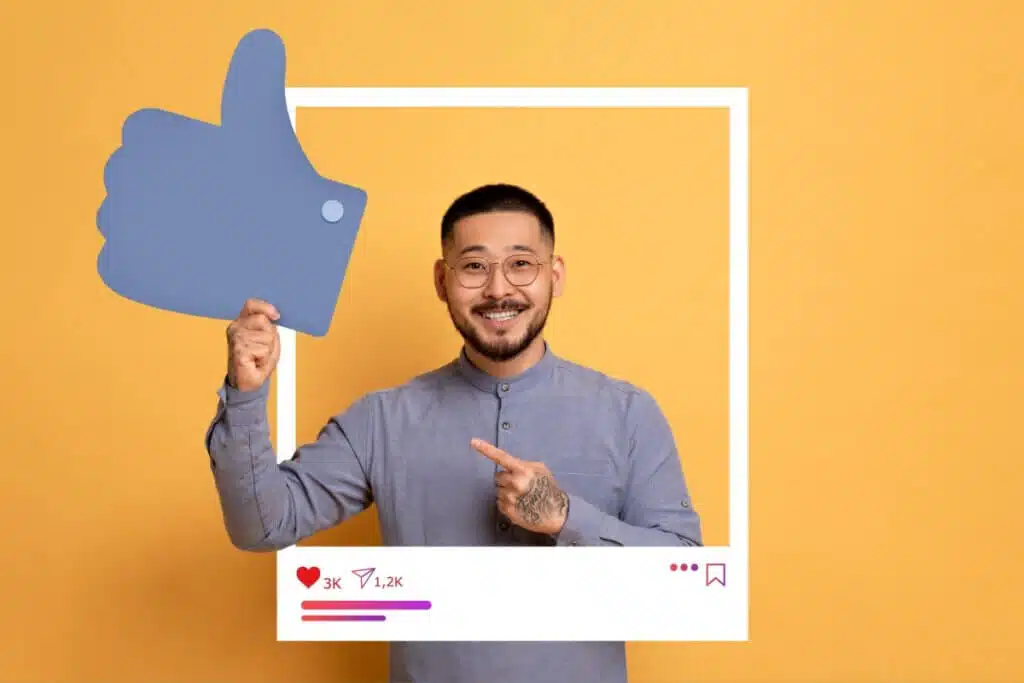 homem de camisa azul sorrindo enquanto segura "like" grande de papel. ele está dentro de post do instagram