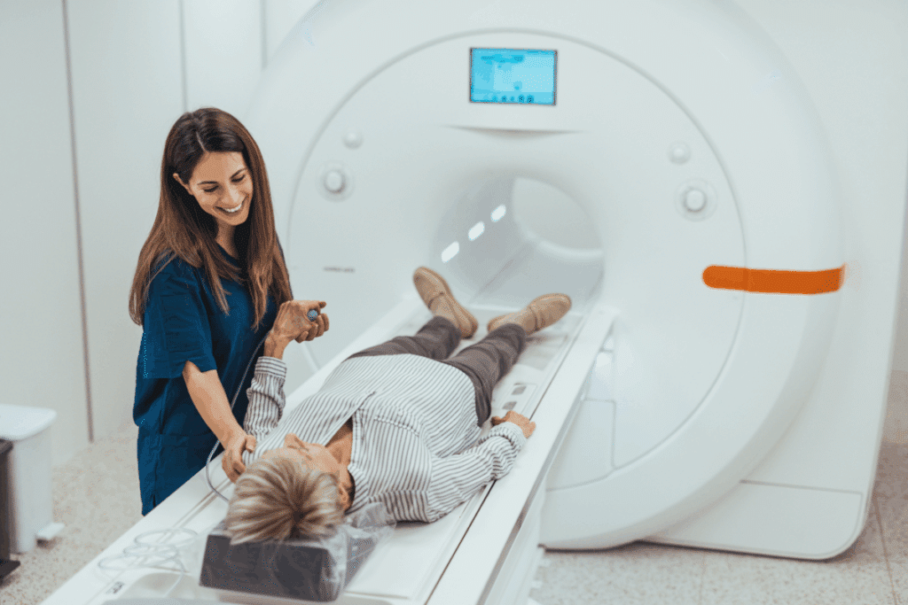 Mulher deitada em máquina de ressonância magnética e enfermeira ao lado conversando com ela