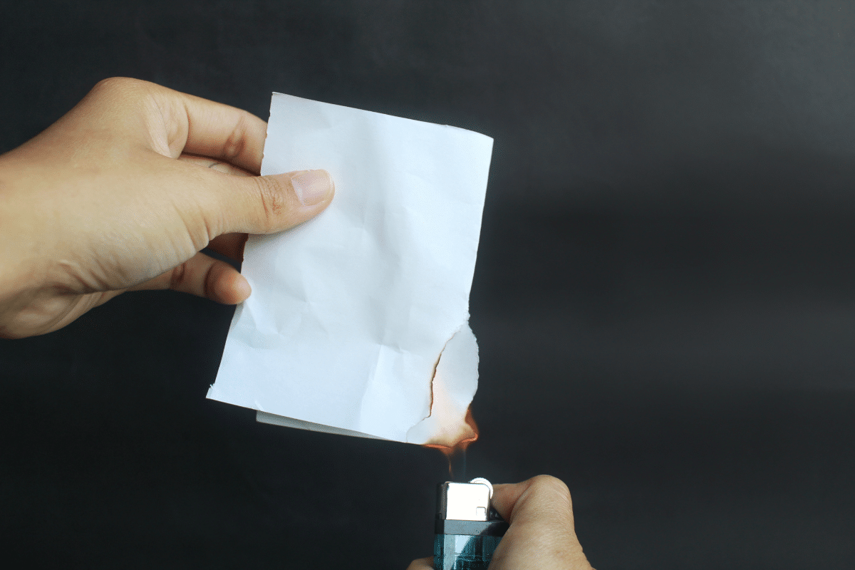 Mãos queimando um papel com isqueiro