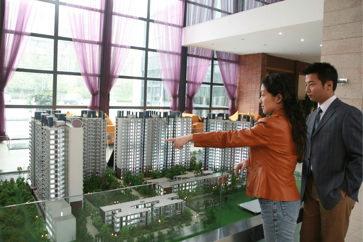 Homem e mulher olhando maquete com torres de prédios 